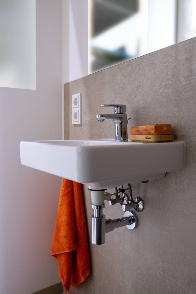 Tjiko-Badezimmer aus dem Projekt Murnau: beige Wandfliesen und orangefarbene Akzente.