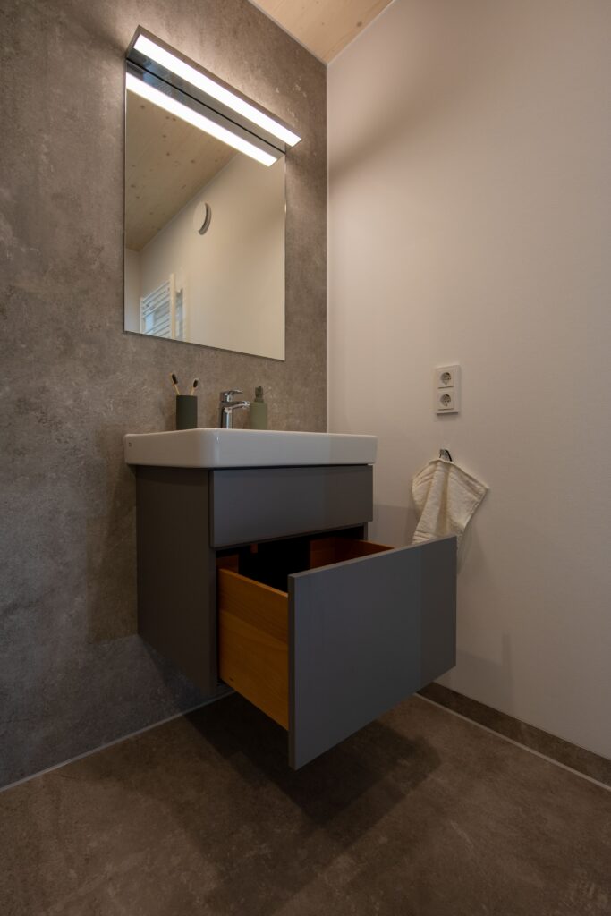 Badezimmer Inverness: Ausschnitt zeigt Waschbecken mit chromfarbener Armatur und Möbelstück.