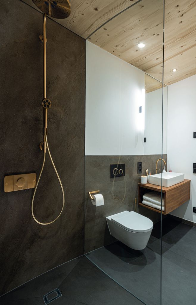 Badezimmer Melbourne: Ausschnitt zeigt WC, Dusche und Waschbecken mit goldfarbener Armatur.