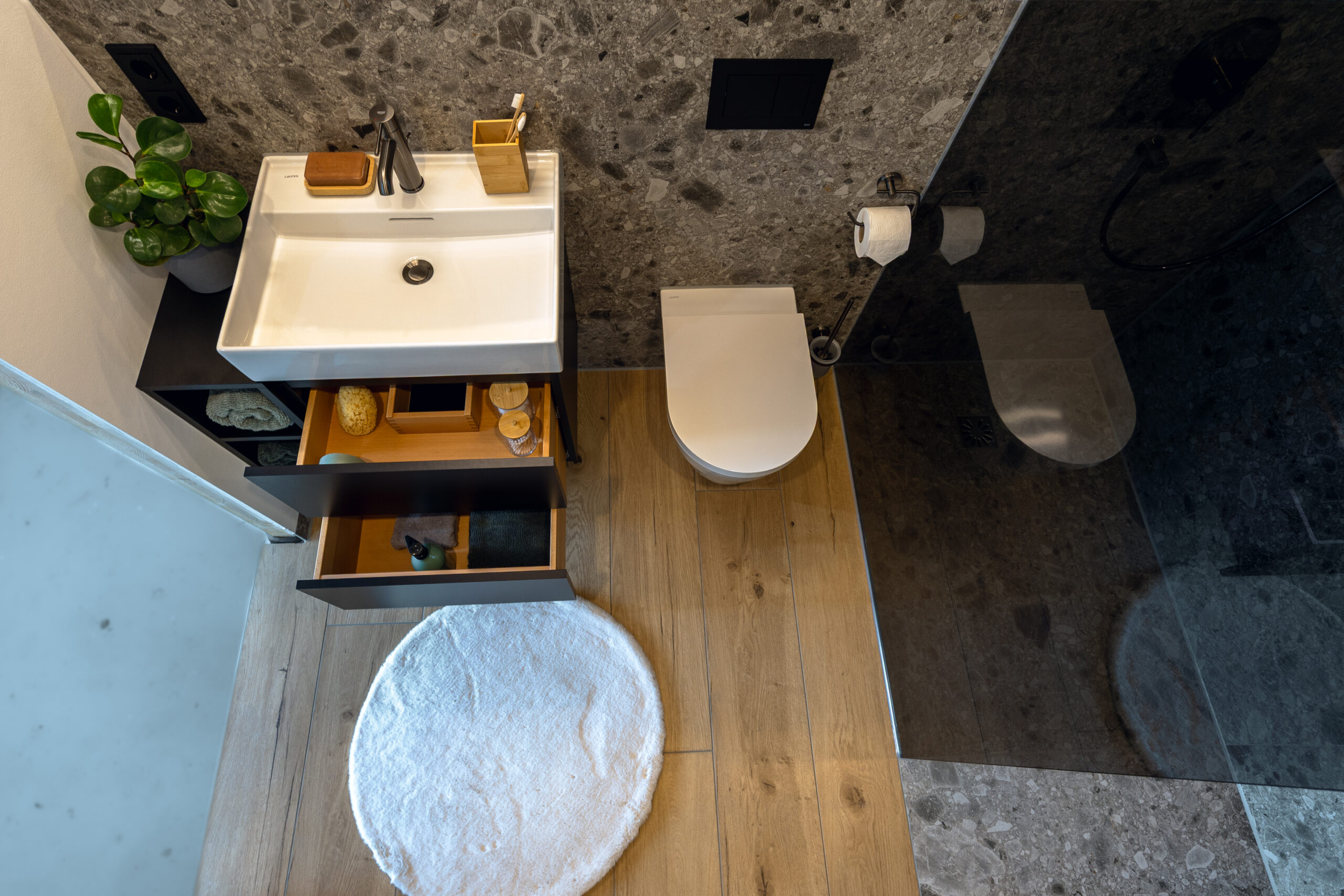 Badezimmer Zermatt: Ausschnitt zeigt WC, Dusche und Waschbecken mit schwarzer Armatur.