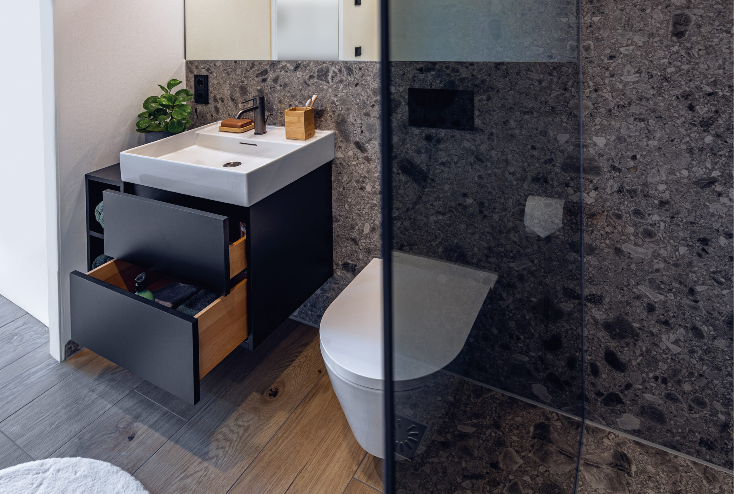 Badezimmer Zermatt: Ausschnitt zeigt WC, Dusche und Waschbecken mit schwarzer Armatur.