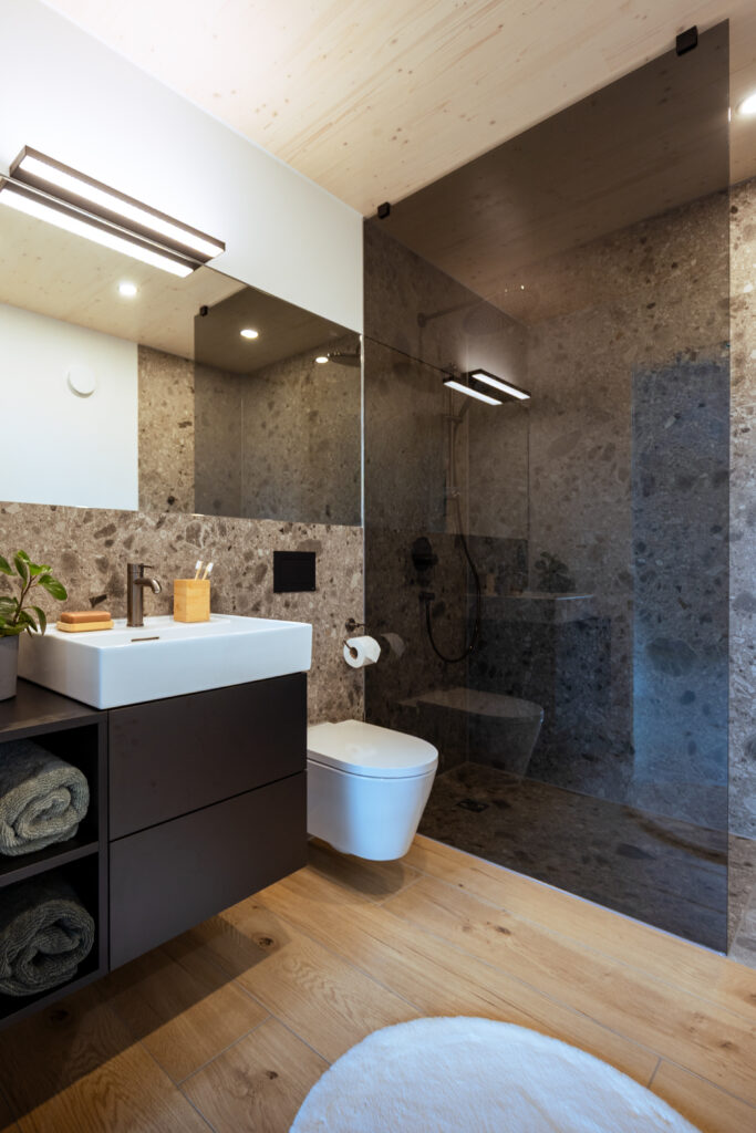 Badezimmer Zermatt: Ausschnitt zeigt WC, Dusche und Waschbecken mit schwarzer Armatur.