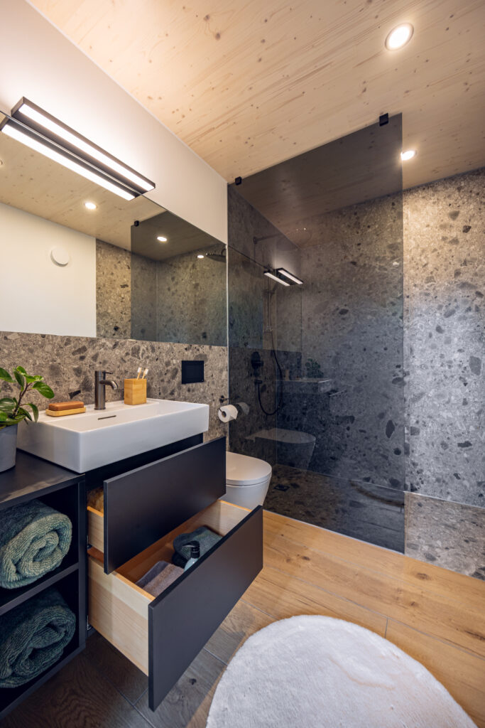 Badezimmer Zermatt: Ausschnitt zeigt WC, Dusche und Waschbecken mit schwarzer Armatur.